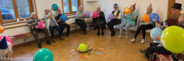 Personen sitzen im Kreis mit Luftballons