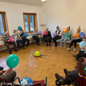 Personen sitzen im Kreis mit Luftballons